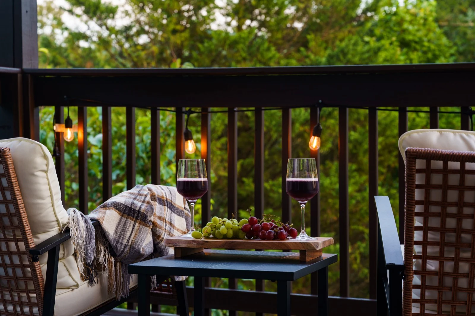 Two wine glasses and a throw on the private primary-suite balcony at evening